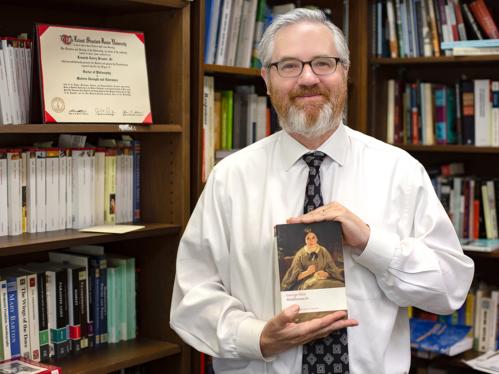 Man holding book in front of bookshelf