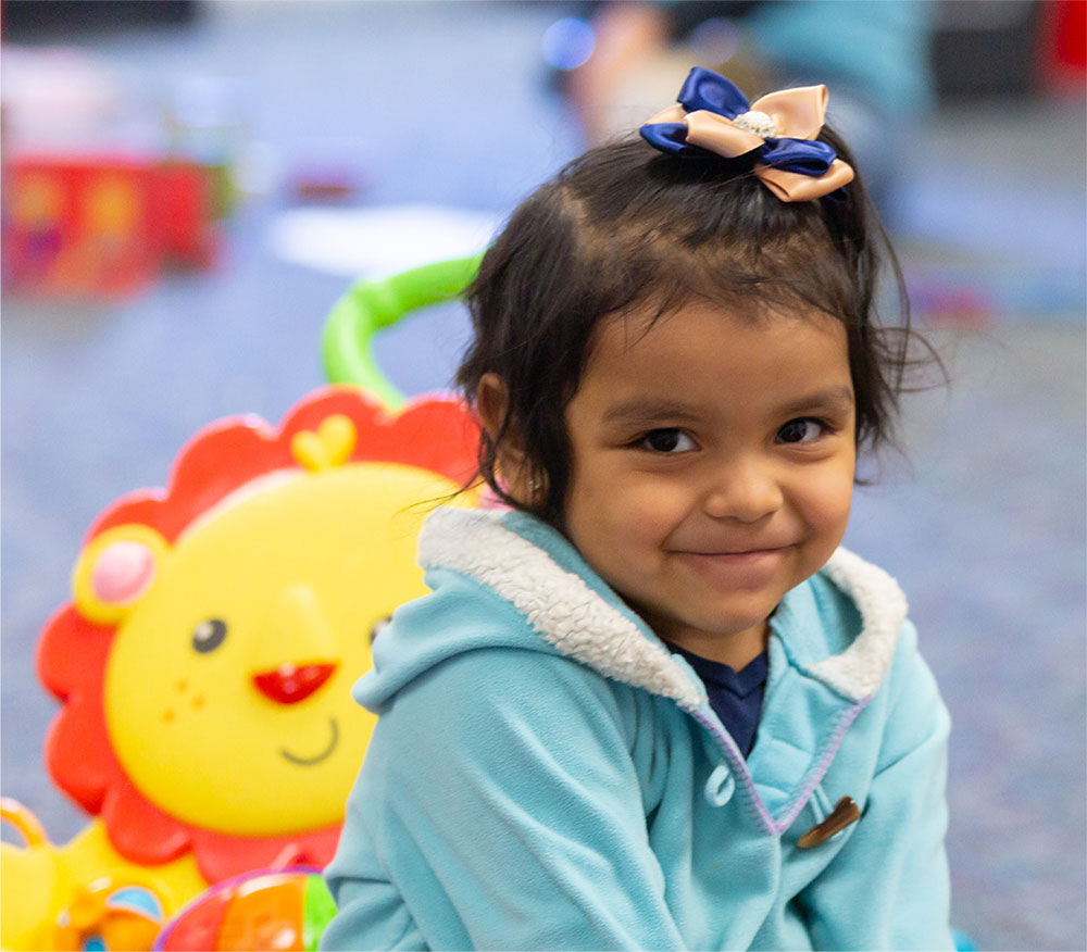 A smiling child with a bow in her hair