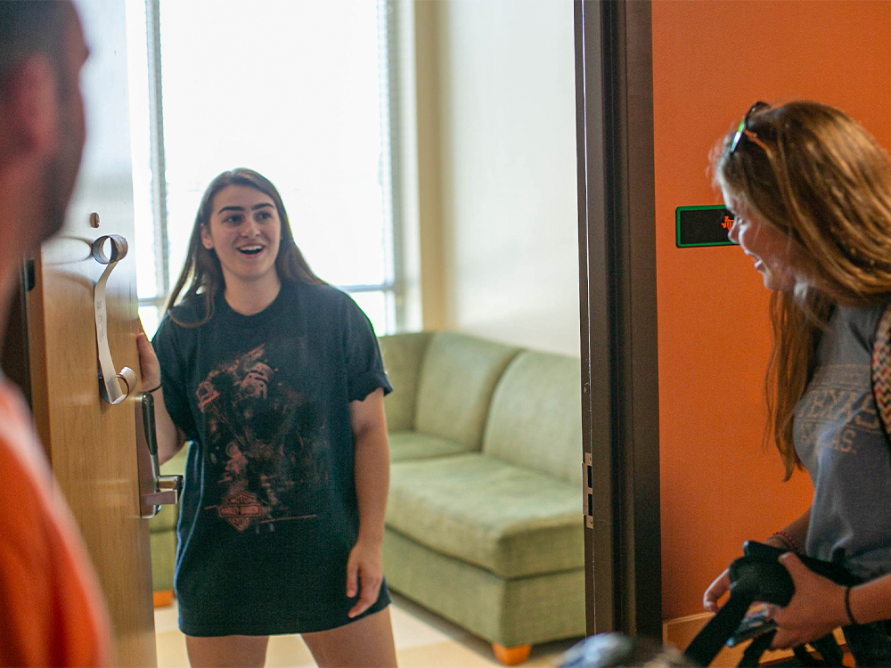 Female student opening door to meet roommate