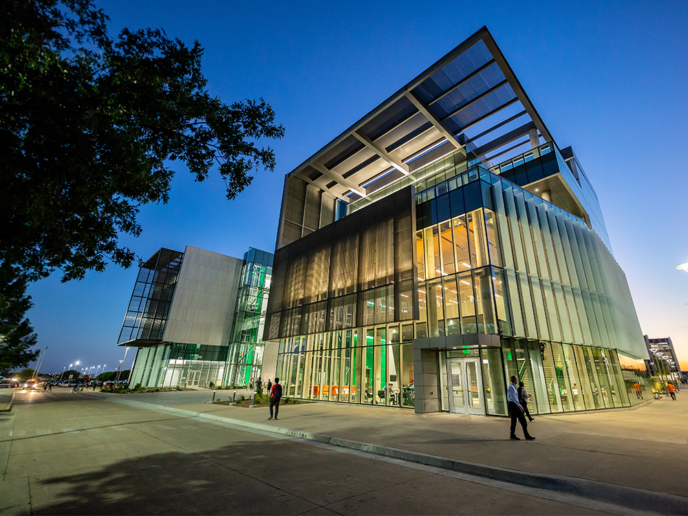 People standing outside E-C-S West at dusk